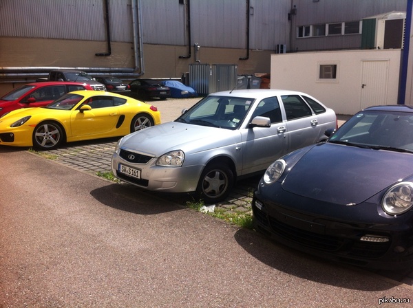 И тут я впал в замешательство Парковка возле Porsche Engineering в Штутгарте. Сделано в августе.  Porsche, приора, лада